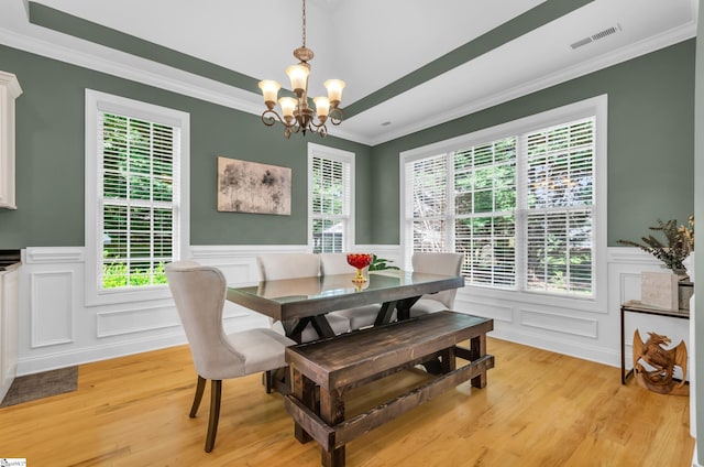 dining room featuring a notable chandelier, a decorative wall, a wainscoted wall, light wood-type flooring, and ornamental molding