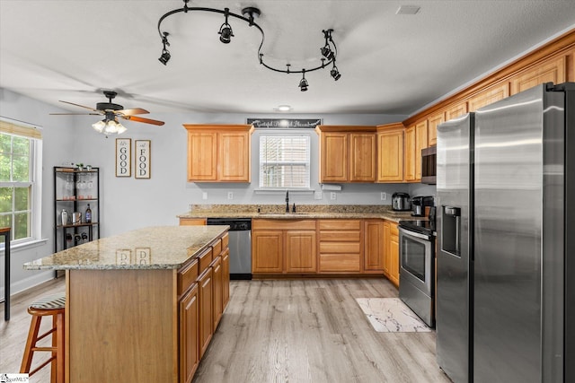 kitchen featuring light wood-style floors, a sink, ceiling fan, and stainless steel appliances