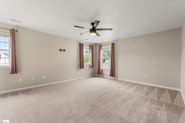 spare room featuring a ceiling fan, baseboards, visible vents, and light carpet