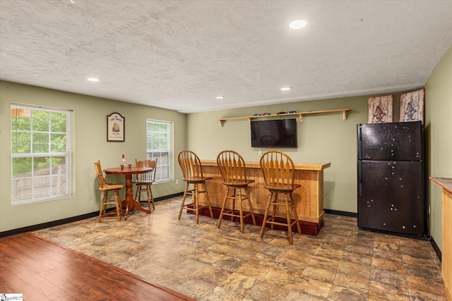 dining space featuring baseboards, a dry bar, recessed lighting, and a textured ceiling