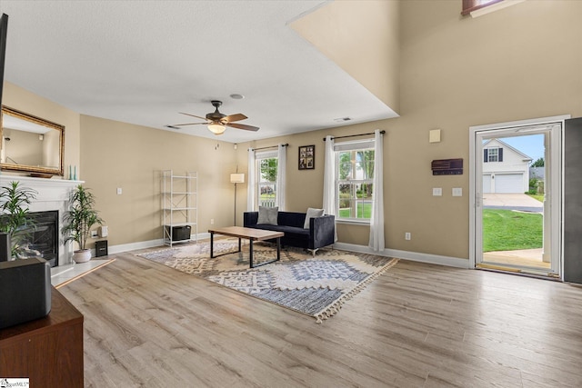 living area with baseboards, a ceiling fan, and wood finished floors
