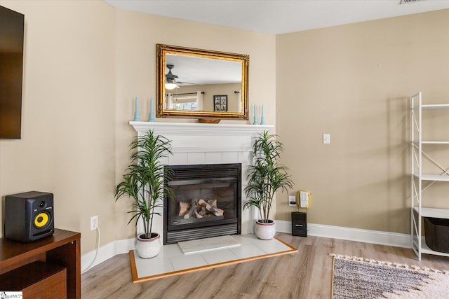 interior space with visible vents, wood finished floors, a fireplace, baseboards, and ceiling fan