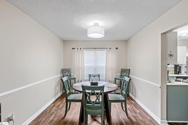 dining space with baseboards, dark wood finished floors, and a textured ceiling