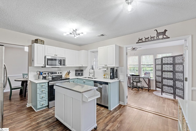 kitchen with visible vents, dark wood-type flooring, a textured ceiling, a sink, and appliances with stainless steel finishes