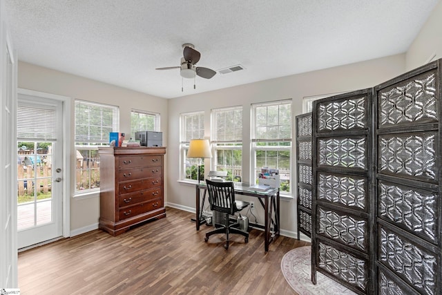 office featuring a textured ceiling, a ceiling fan, baseboards, wood finished floors, and visible vents