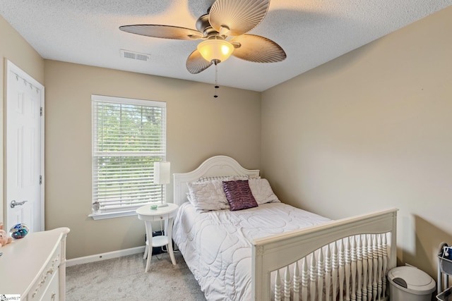bedroom with a ceiling fan, a textured ceiling, visible vents, light colored carpet, and baseboards