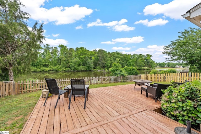 wooden deck with a fenced backyard, outdoor dining area, and a water view
