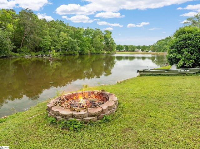 property view of water with an outdoor fire pit and a wooded view