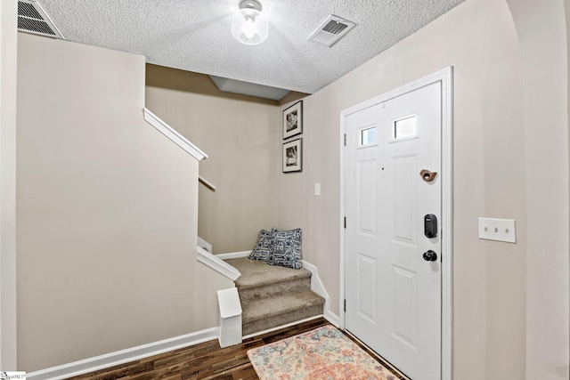 entrance foyer featuring stairs, a textured ceiling, and visible vents