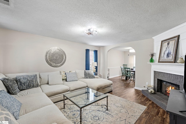 living area with visible vents, arched walkways, a textured ceiling, and dark wood-type flooring