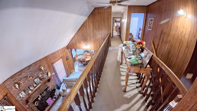 stairway with wooden walls, vaulted ceiling, and carpet