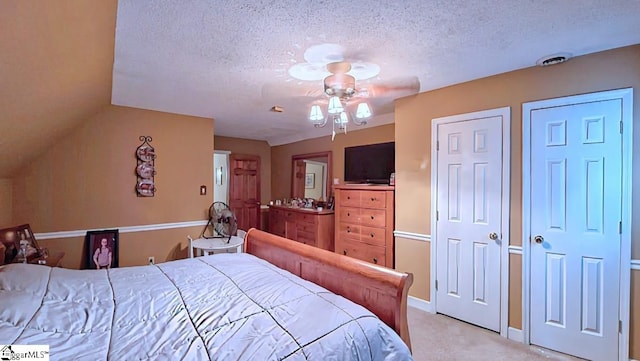bedroom featuring baseboards, light carpet, two closets, and a textured ceiling