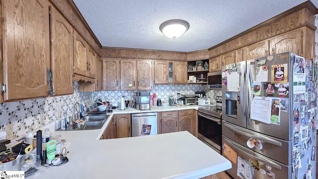 kitchen featuring a textured ceiling, light countertops, a sink, a peninsula, and stainless steel appliances