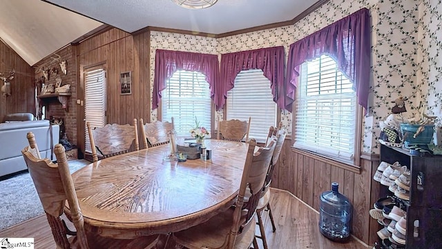 dining area with plenty of natural light, wood walls, and wood finished floors