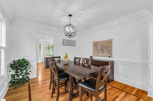 dining area featuring crown molding, light wood-style flooring, and a notable chandelier