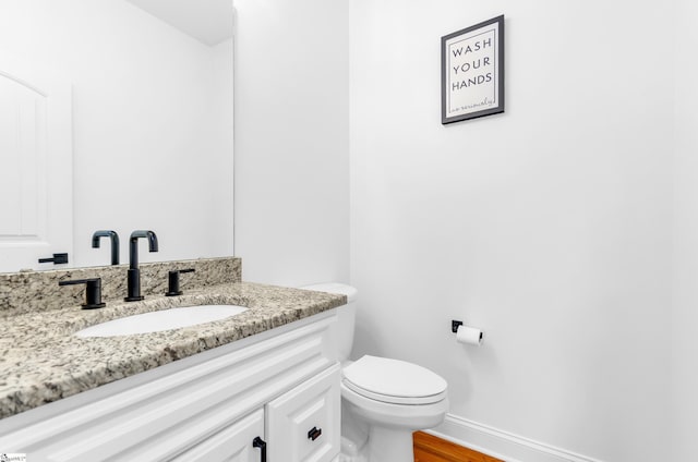 bathroom featuring vanity, baseboards, toilet, and wood finished floors