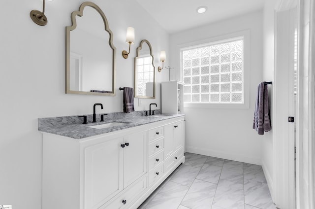 bathroom featuring a sink, baseboards, double vanity, and marble finish floor