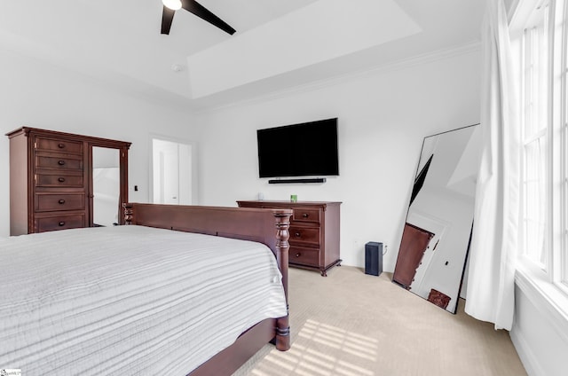 bedroom with a raised ceiling, ceiling fan, ornamental molding, and light colored carpet