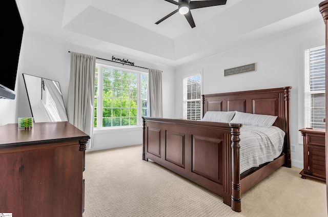 bedroom featuring a ceiling fan, a tray ceiling, and light colored carpet