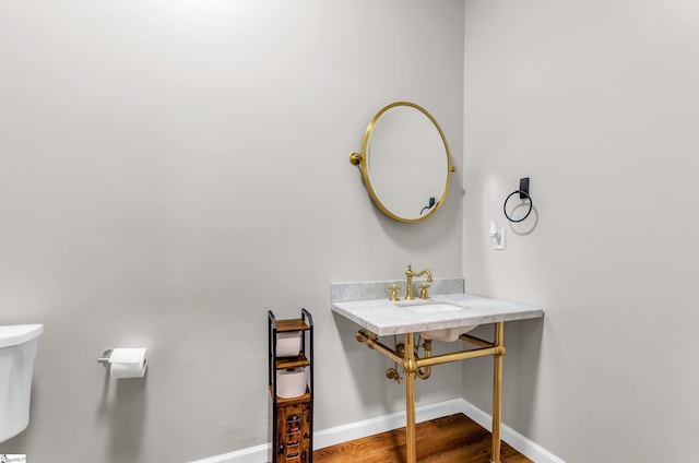 bathroom featuring a sink, baseboards, toilet, and wood finished floors