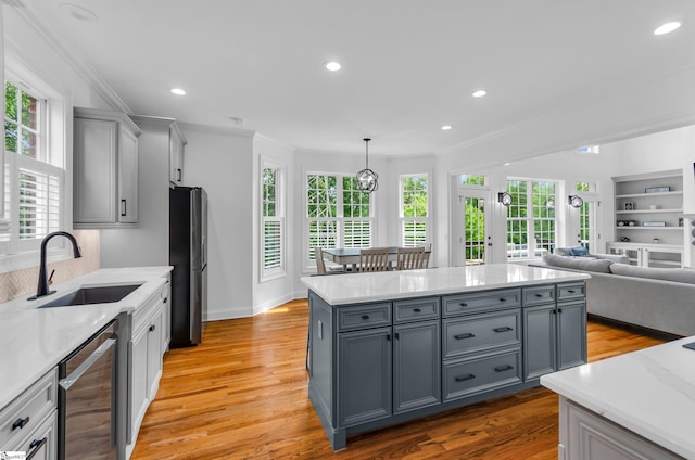 kitchen featuring a sink, beverage cooler, gray cabinets, freestanding refrigerator, and a healthy amount of sunlight