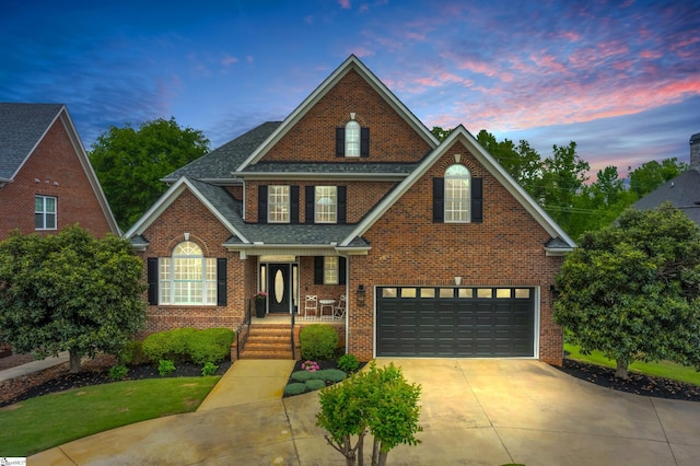 traditional-style house featuring brick siding, driveway, roof with shingles, and a garage