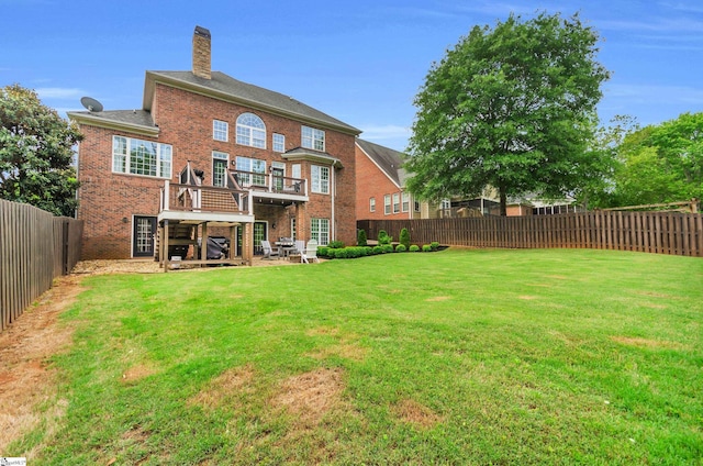 back of property with a lawn, a fenced backyard, brick siding, and a chimney