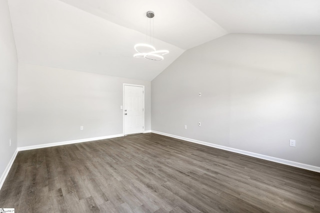 interior space with baseboards, vaulted ceiling, and dark wood-style floors