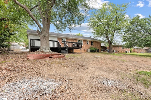 back of house featuring fence, a deck, and brick siding