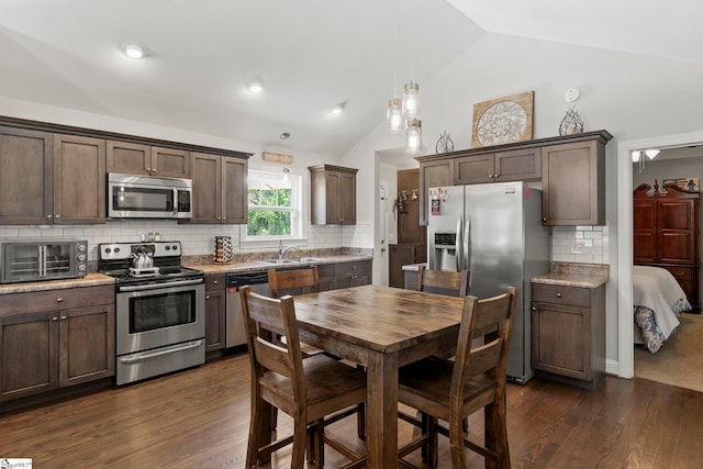 kitchen featuring a toaster, dark brown cabinetry, a sink, appliances with stainless steel finishes, and vaulted ceiling