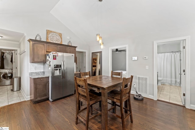 dining room featuring a ceiling fan, dark wood-style flooring, washer / clothes dryer, visible vents, and lofted ceiling