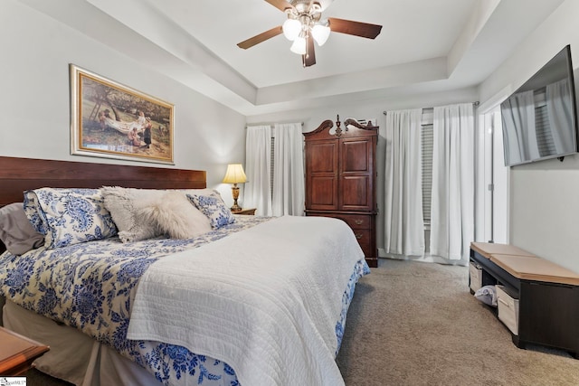 bedroom with a ceiling fan, light carpet, and a tray ceiling
