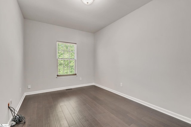 unfurnished room featuring dark wood-style flooring, baseboards, and visible vents