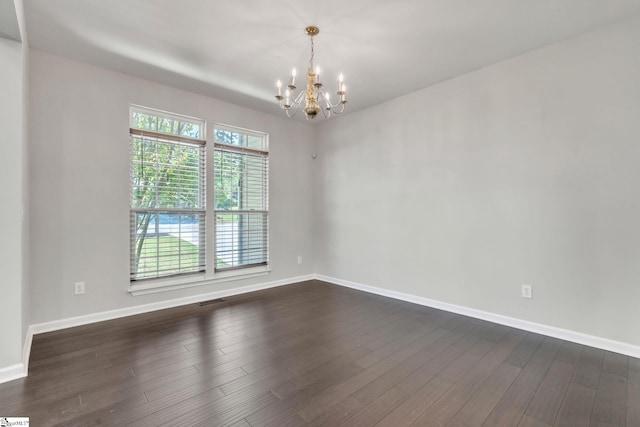 unfurnished room featuring baseboards, dark wood-type flooring, a notable chandelier, and visible vents