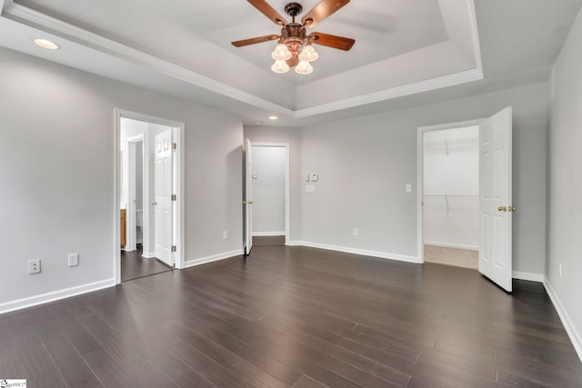 interior space featuring recessed lighting, baseboards, a walk in closet, and a tray ceiling