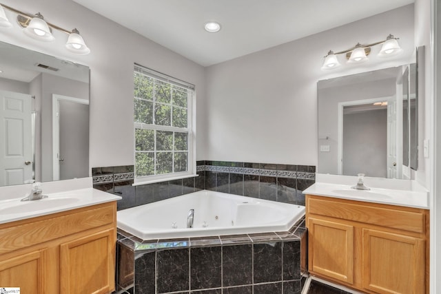 full bathroom with a whirlpool tub, visible vents, two vanities, and a sink