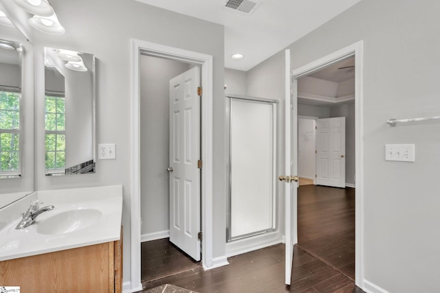 full bath featuring visible vents, a shower stall, wood finished floors, vanity, and baseboards