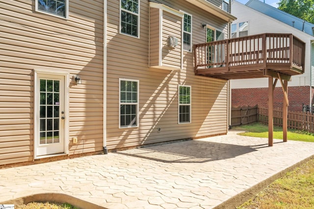 rear view of property featuring fence, a patio area, and a deck