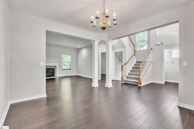 unfurnished living room with a fireplace, baseboards, stairway, a chandelier, and dark wood finished floors