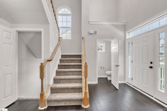 foyer featuring plenty of natural light, stairs, dark wood-style flooring, and baseboards