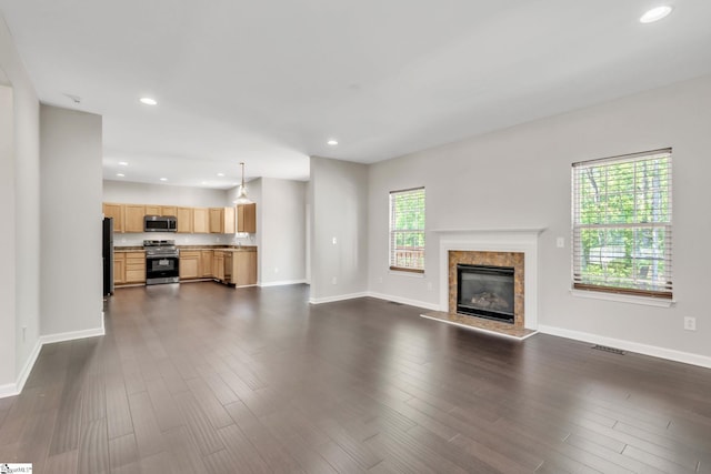 unfurnished living room featuring dark wood-style flooring, a premium fireplace, recessed lighting, baseboards, and visible vents