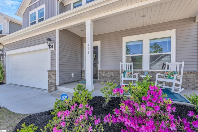 entrance to property with a garage, brick siding, board and batten siding, concrete driveway, and a porch
