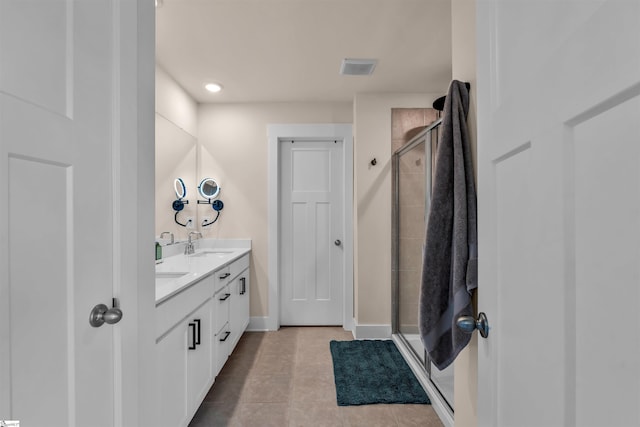 bathroom featuring double vanity, a sink, a stall shower, and tile patterned floors