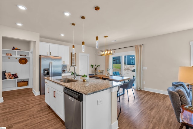 kitchen with stainless steel appliances, a center island with sink, a sink, and wood finished floors