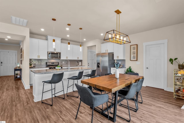 dining room with light wood finished floors, a chandelier, recessed lighting, baseboards, and visible vents