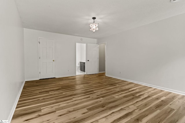 unfurnished bedroom with baseboards, ensuite bath, and wood finished floors