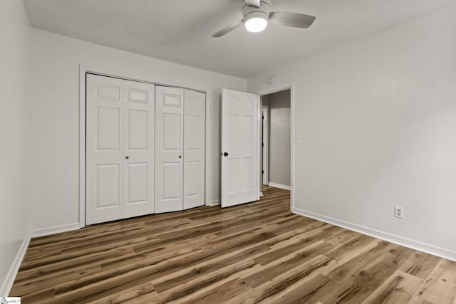 unfurnished bedroom with baseboards, ceiling fan, a closet, and wood finished floors