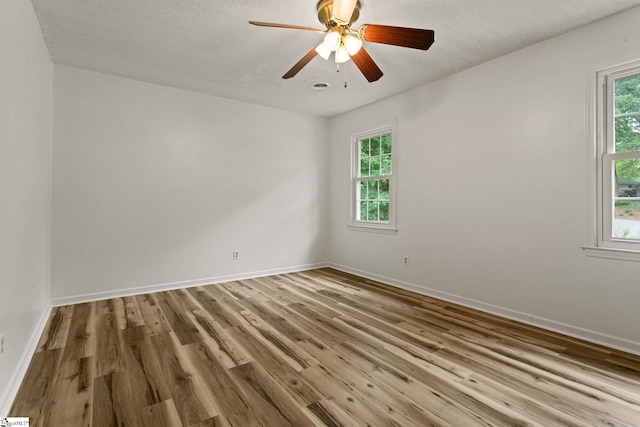 empty room featuring baseboards, a wealth of natural light, and wood finished floors