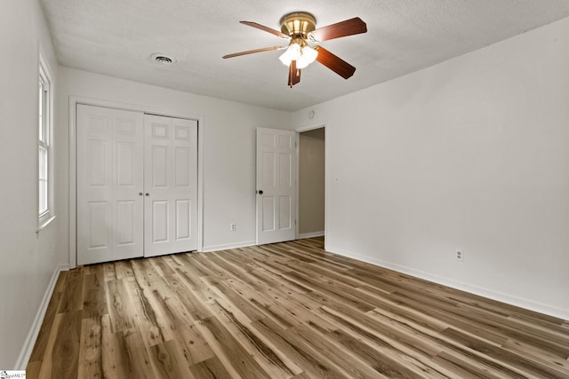 unfurnished bedroom with baseboards, ceiling fan, a closet, and wood finished floors