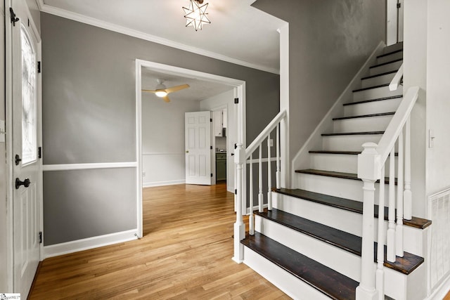 foyer entrance featuring ornamental molding, a ceiling fan, stairs, and wood finished floors